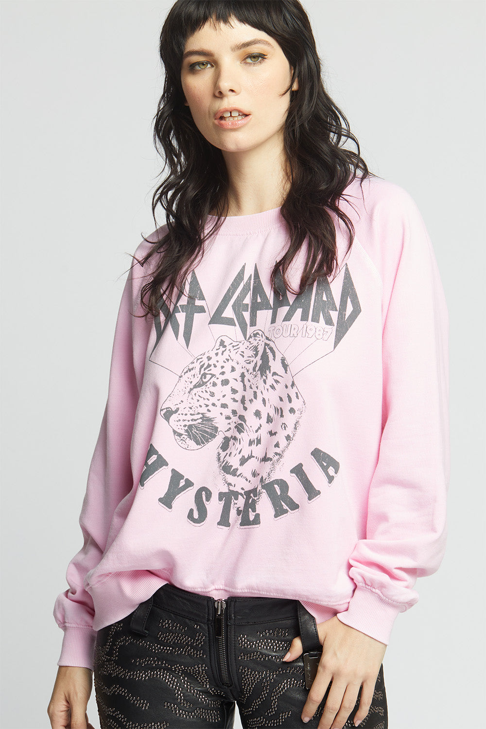 Person wearing a pink sweatshirt with a graphic design on a plain background